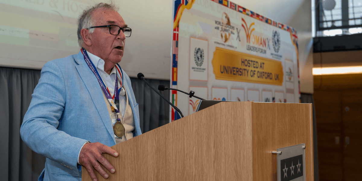 An older man speaks at a podium during a university event or conference