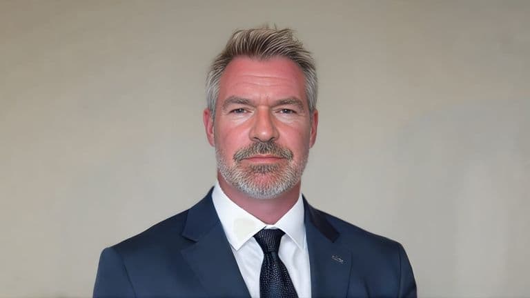 Portrait of Jason Butcher in a navy suit and tie against a neutral background.
