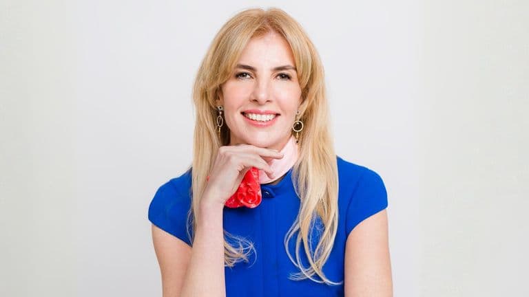 A woman with long blonde hair wearing a blue shirt, representing leadership in AI-driven corporate transformation.