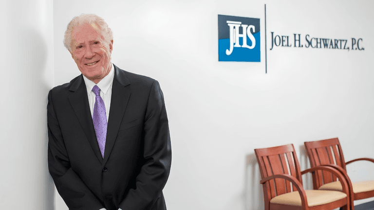 Joel H. Schwartz standing in the firm's Boston office beside the Joel H. Schwartz, P.C. sign.