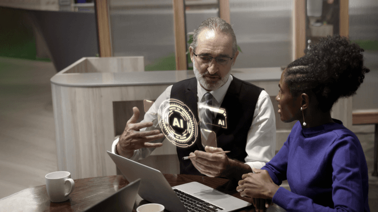 Two professionals discussing AI strategy at a table with a laptop and digital AI interface graphic.