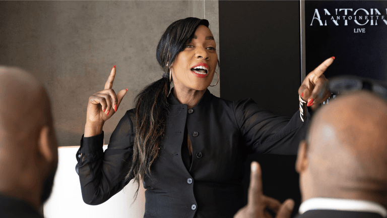"Antoinette Antoine, executive coach, speaking passionately to a group, guiding high-level leaders through personal and professional reinvention."