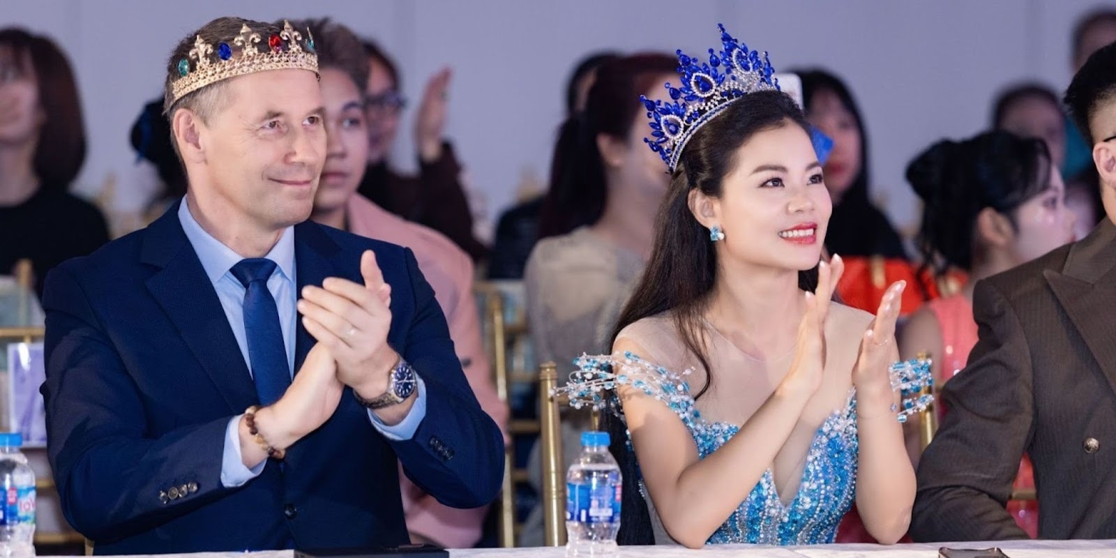 Tan Le and Dieter Bruhn, crowned Miss & Mister Mighty Entrepreneur International 2025, applauding at an event together.
