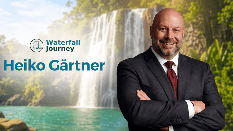 Man in a suit smiling against a scenic waterfall background with text overlay