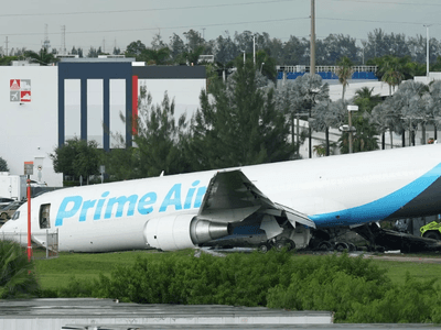 A Prime Air cargo plane is damaged and partially crashed on a grassy area