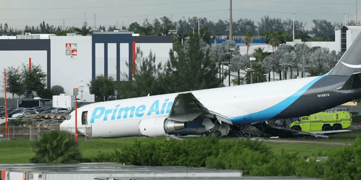 A Prime Air cargo plane is damaged and partially crashed on a grassy area