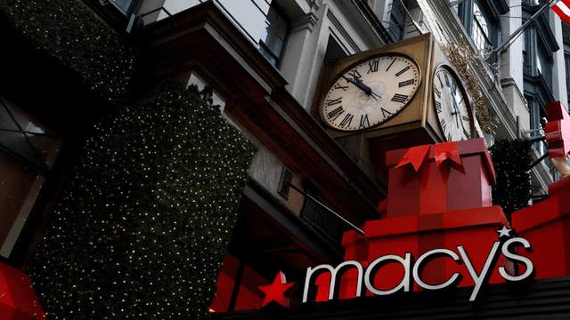 Macy's storefront adorned with holiday decorations, clock, and large red gift boxes