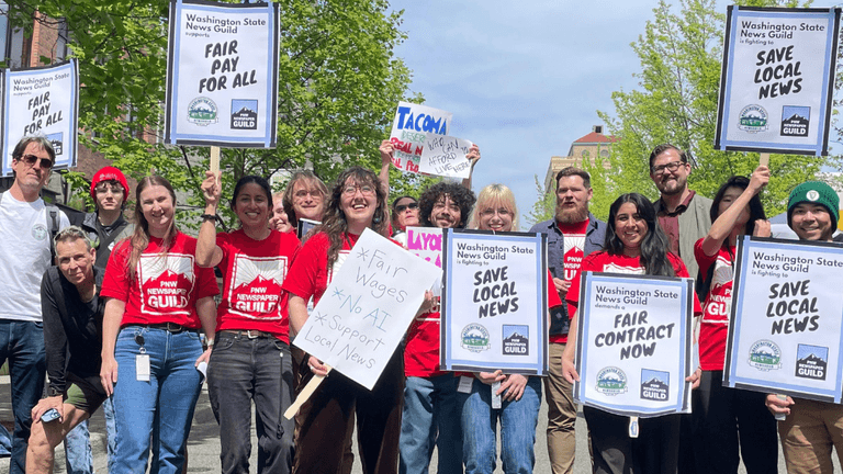 Group of protesters holding signs advocating for fair pay and local news support