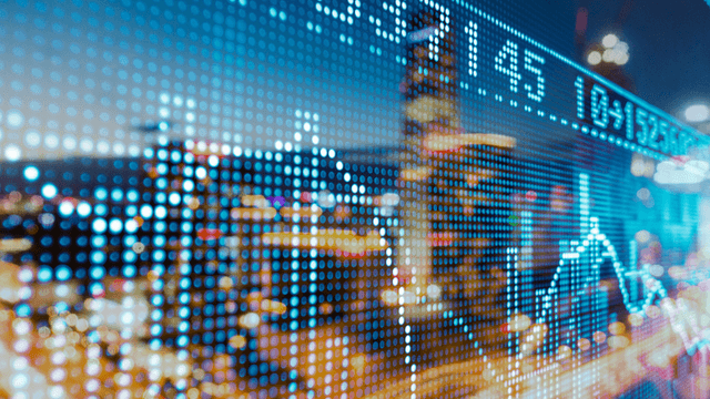 Digital stock market data overlaying a blurred cityscape at night