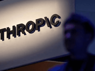 Sign for Anthropic illuminated with a blurred silhouette of a person in the foreground