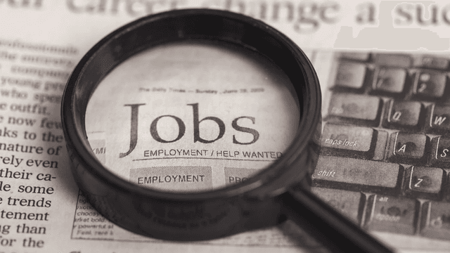 Magnifying glass over a newspaper with the word "Jobs" highlighted prominently