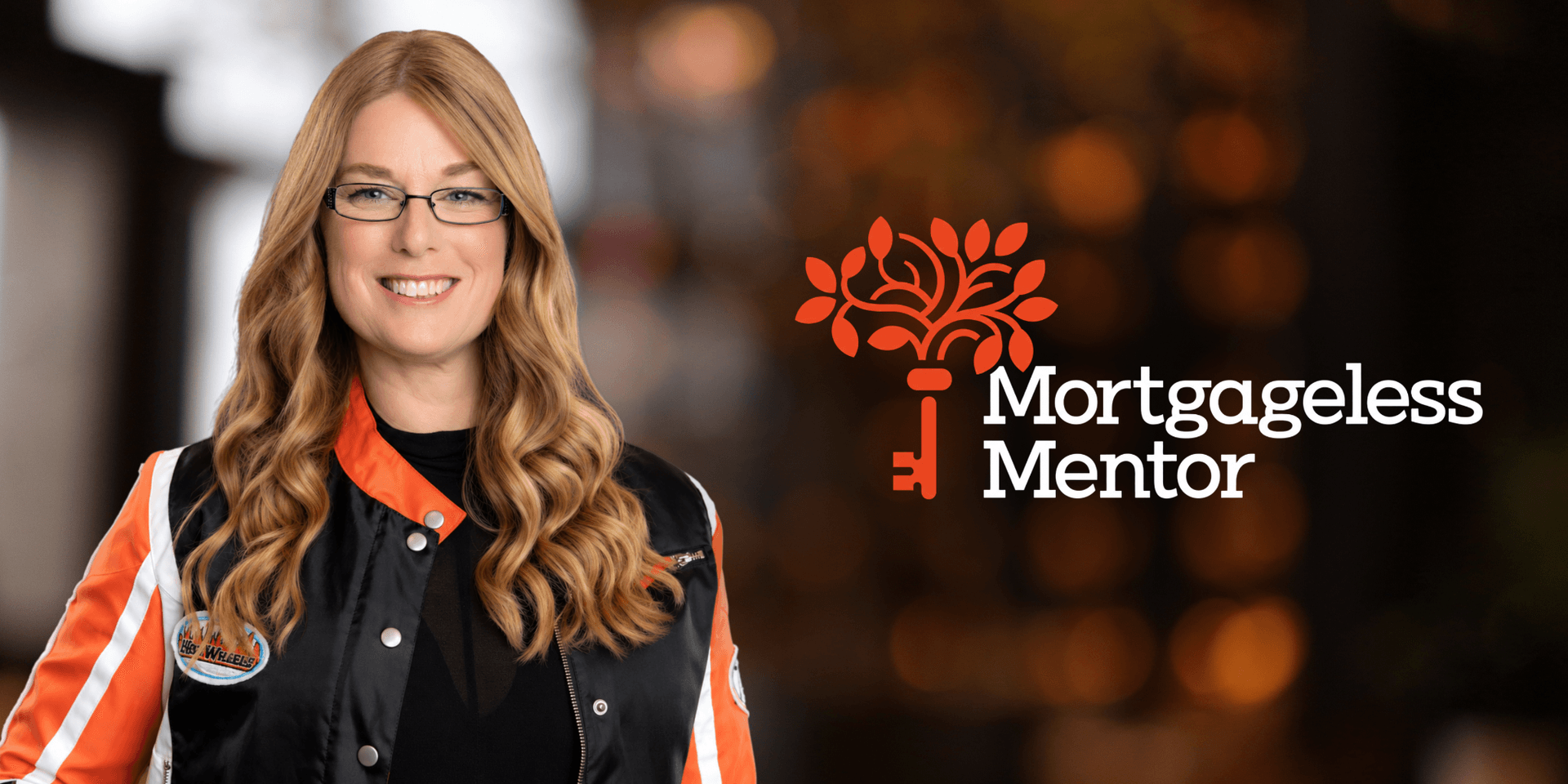 Woman with long hair in a black and orange jacket smiling beside a logo