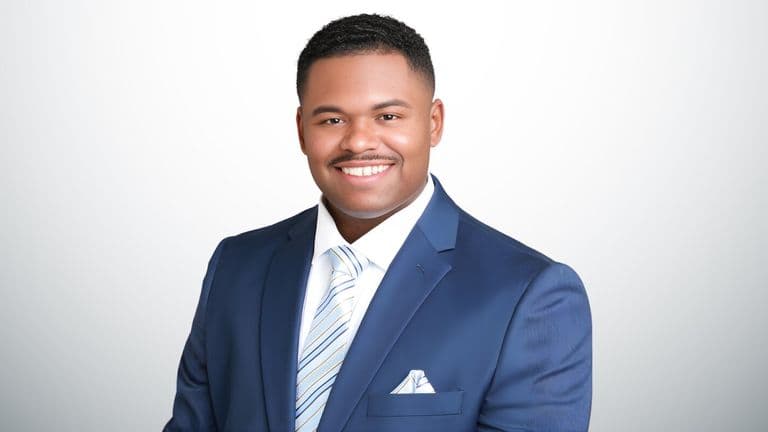 Daniel McDavid, a black man in a blue suit and tie, symbolizes the mission of Move Mountains Credit Repair.