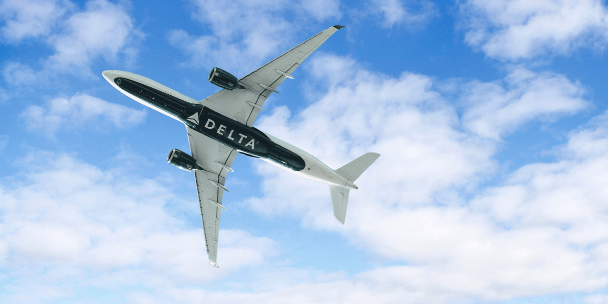 Delta Air Lines aircraft flying overhead against a blue sky with scattered clouds.