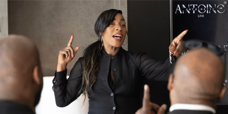 "Antoinette Antoine, executive coach, speaking passionately to a group, guiding high-level leaders through personal and professional reinvention."