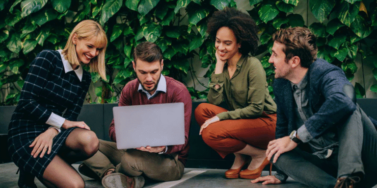 A diverse group of professionals collaborating on a laptop in a modern office setting.