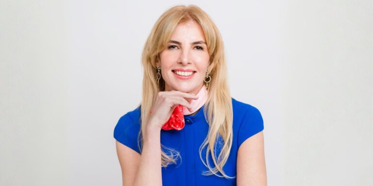 A woman with long blonde hair wearing a blue shirt, representing leadership in AI-driven corporate transformation.
