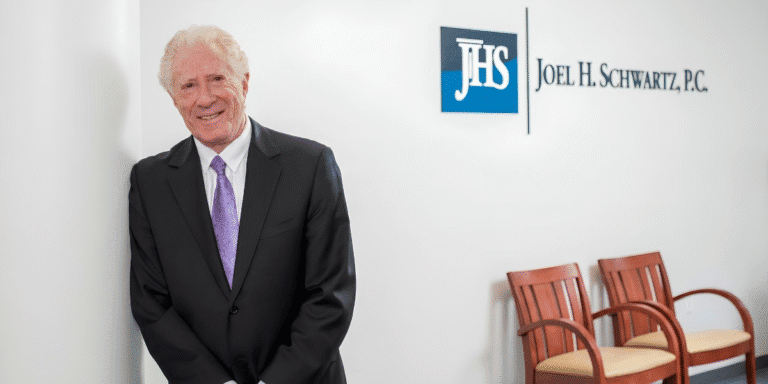 What Six Decades Of Local Experience Means For Boston Injury Victims Joel H. Schwartz standing in the firm's Boston office beside the Joel H. Schwartz, P.C. sign.