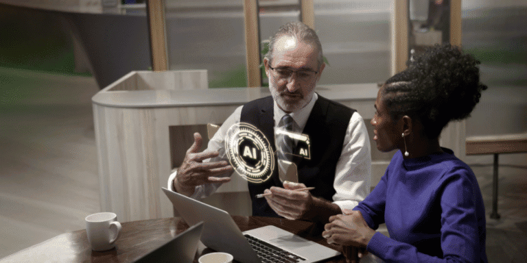Leadership Under Pressure: What the Next Wave of AI Investment Means for Business Decision-Makers Two professionals discussing AI strategy at a table with a laptop and digital AI interface graphic.